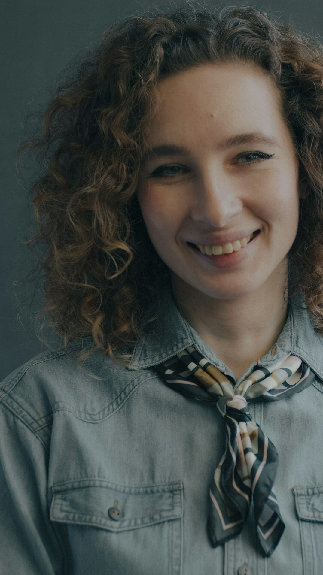 Studio portrait of a woman with a scarf smiling