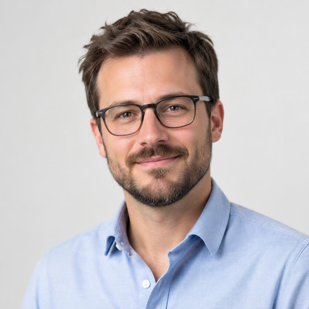 Studio portrait of a man with glasses and a beard smiling